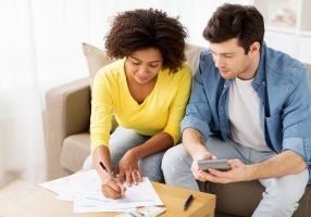 family budget, finances and people concept - couple with papers and calculator counting money at home